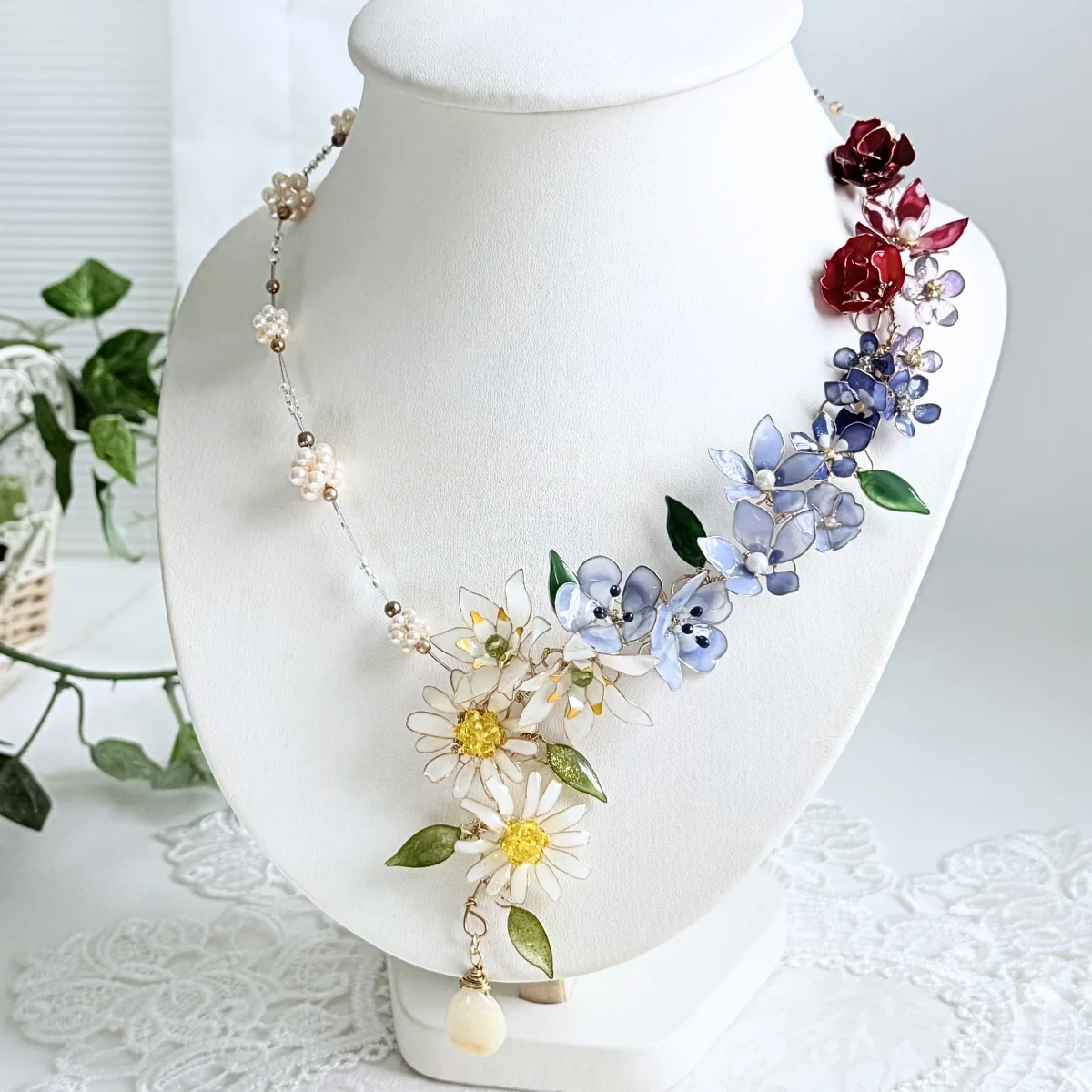 白いトルソーに飾ったマニキュア花ジュエリー®のネックレス作品